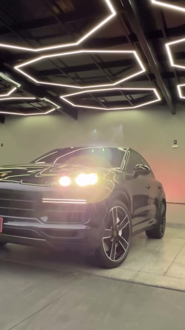Porsche Cayenne preto com pintura espelhada sob a iluminação hexagonal do box